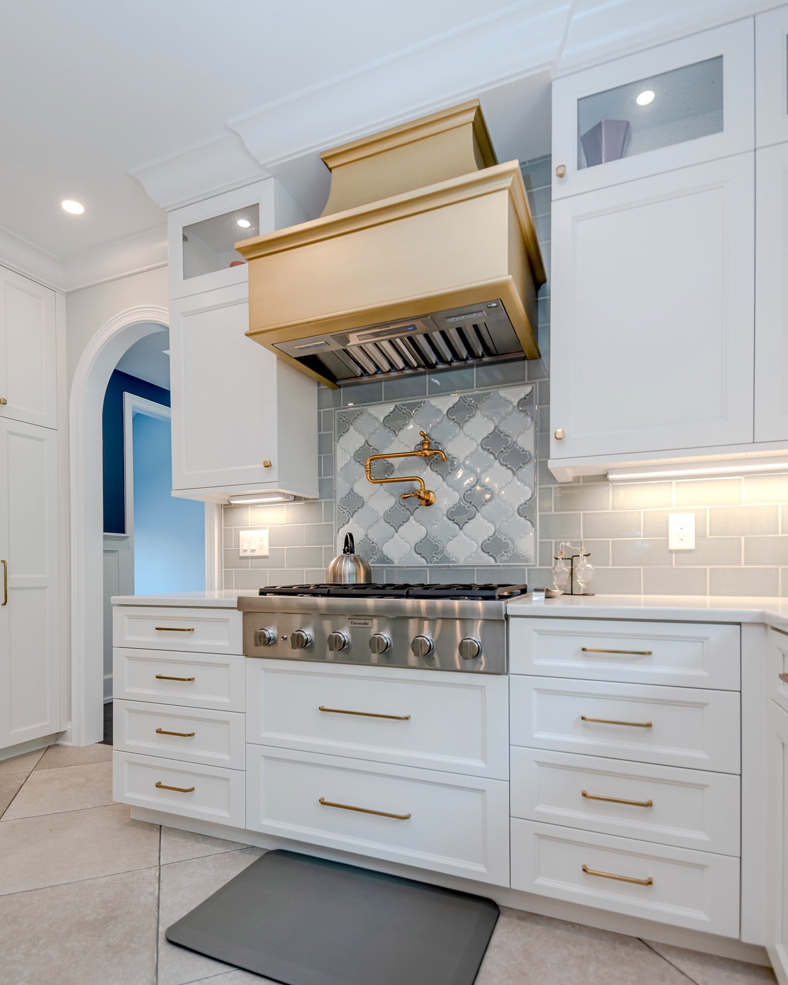 Kitchen remodel in Chagrin Falls, Ohio with gold cabinet handles and oven vent with white cabinets