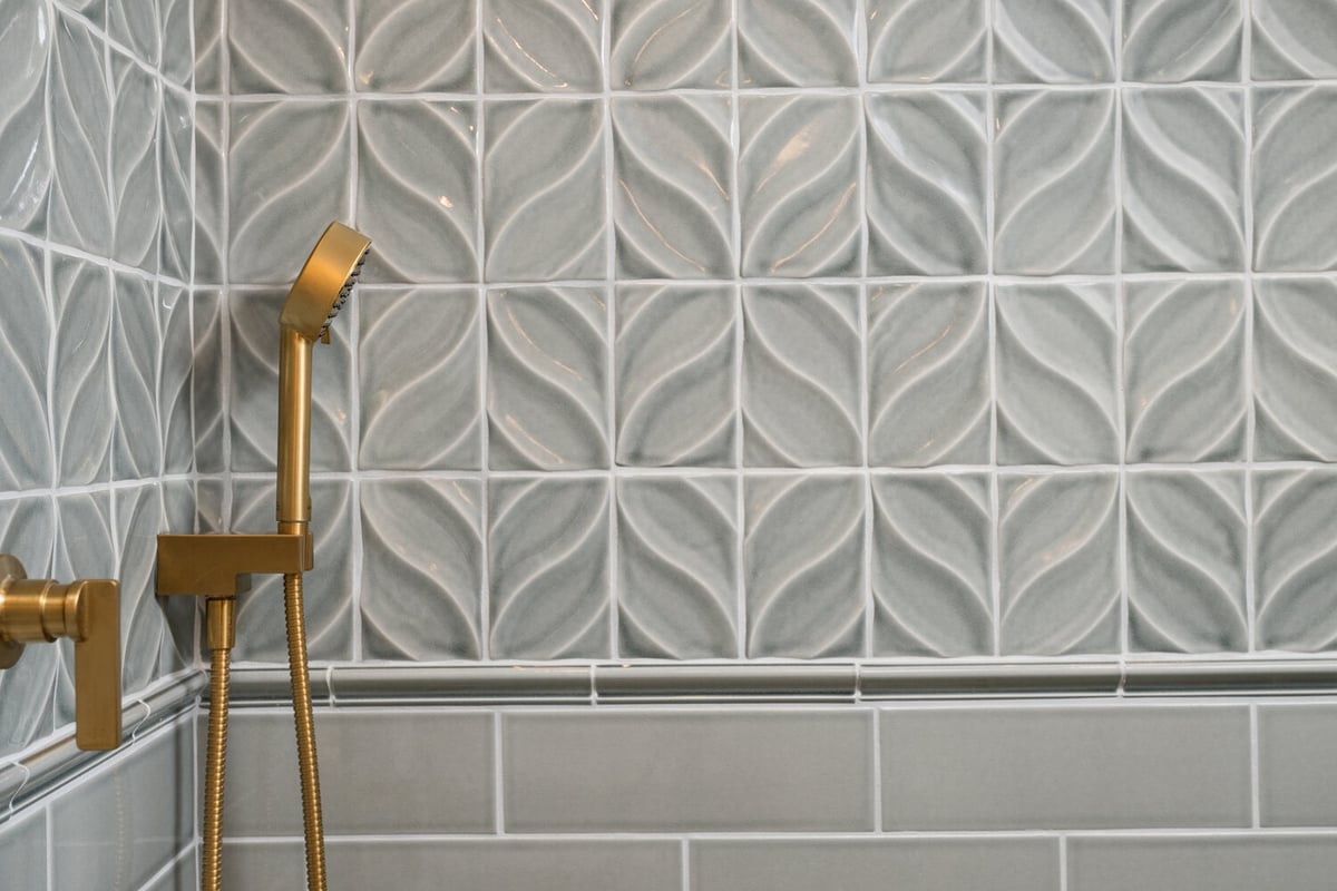 custom bathroom shower with textured tile and gold accents by Chagrin River Company in Hunting Valley, OH