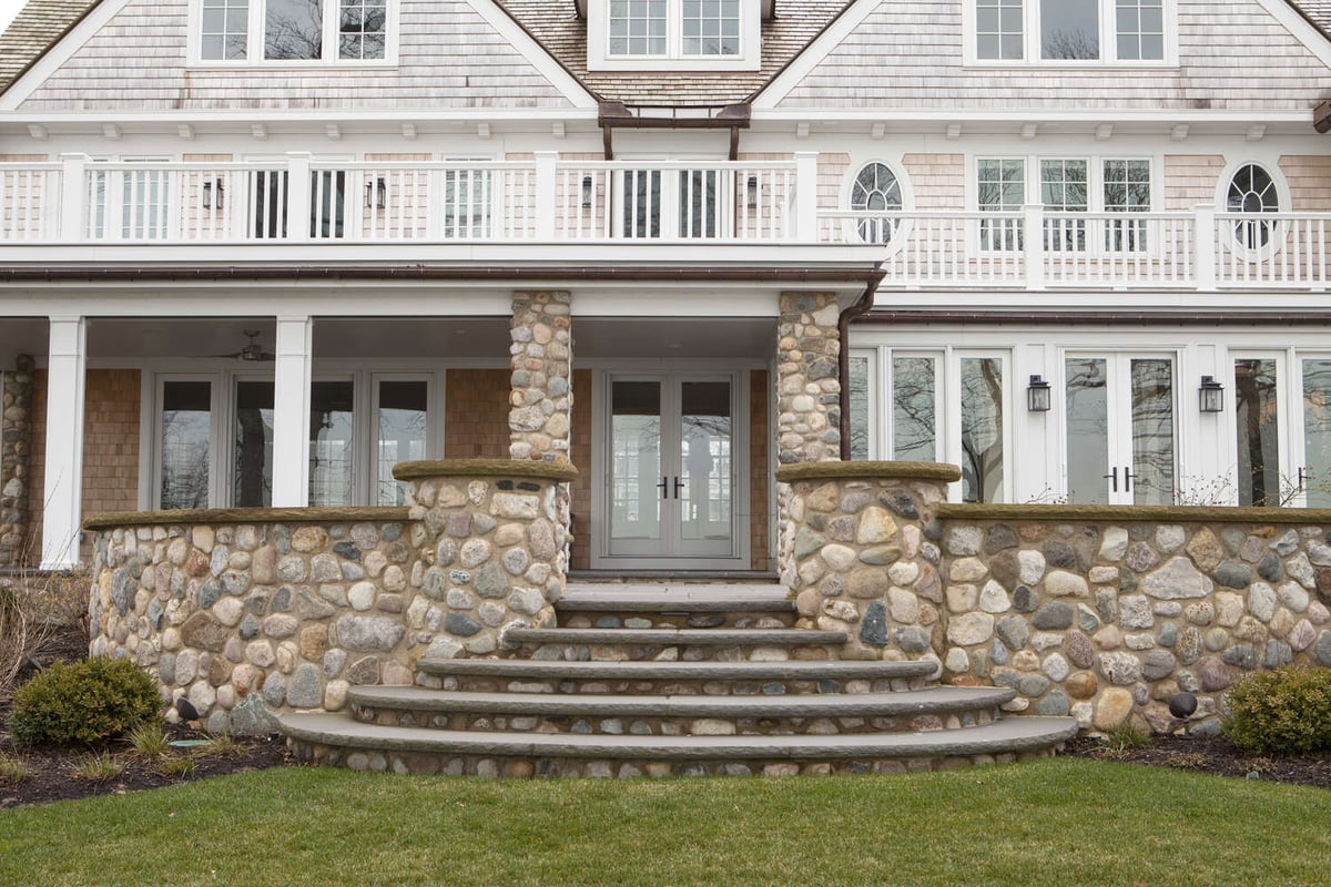 lakefront home exterior with stone steps and covered porch by Chagrin River Company in Bainbridge, OH