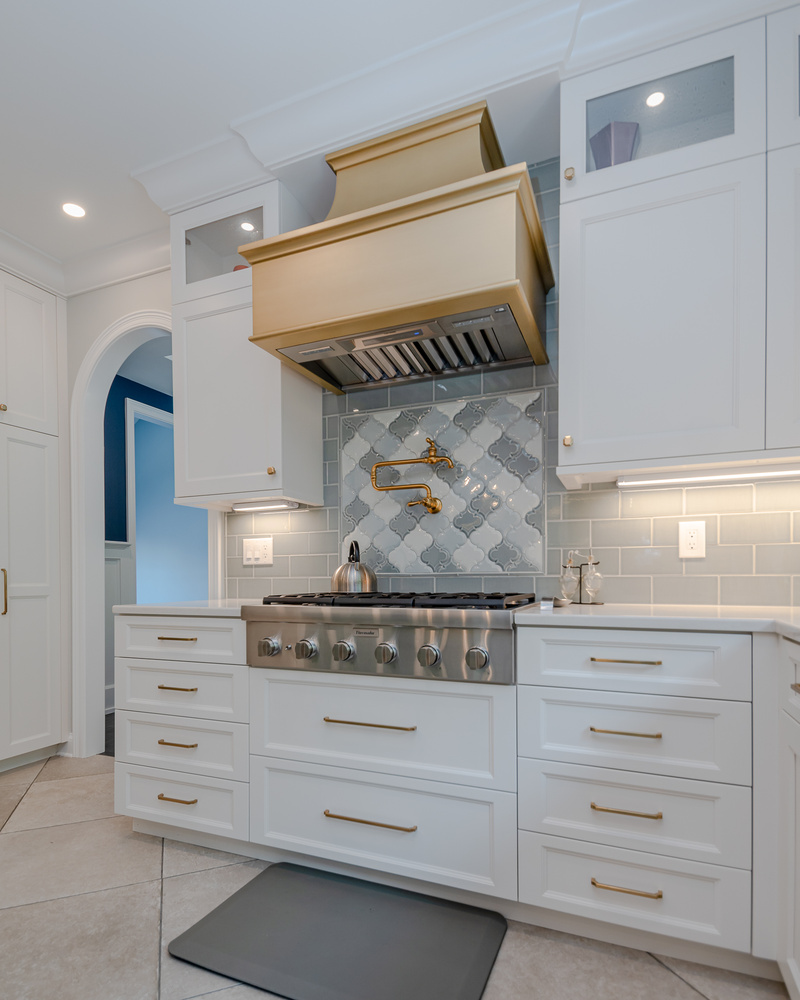 kitchen remodel with gold range hood and patterned tile backsplash by Chagrin River Company in Pepper Pike, OH