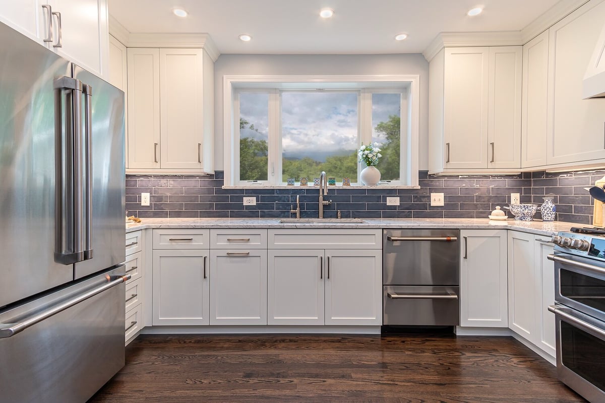 kitchen remodel with white cabinets and dark blue backsplash by Chagrin River Company in Bainbridge, OH