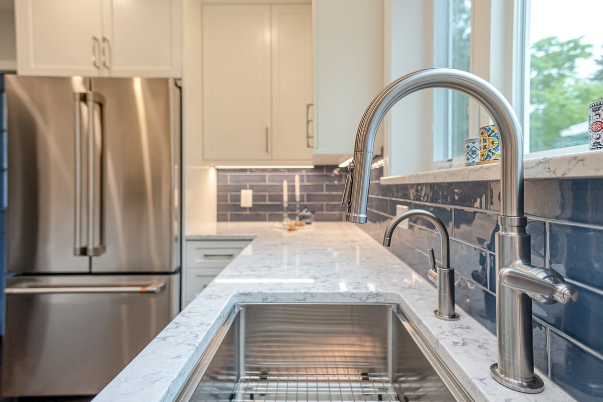close-up of custom home kitchen sink in Euclid, OH built by Chagrin River Company with marble countertop and blue tile backsplash.