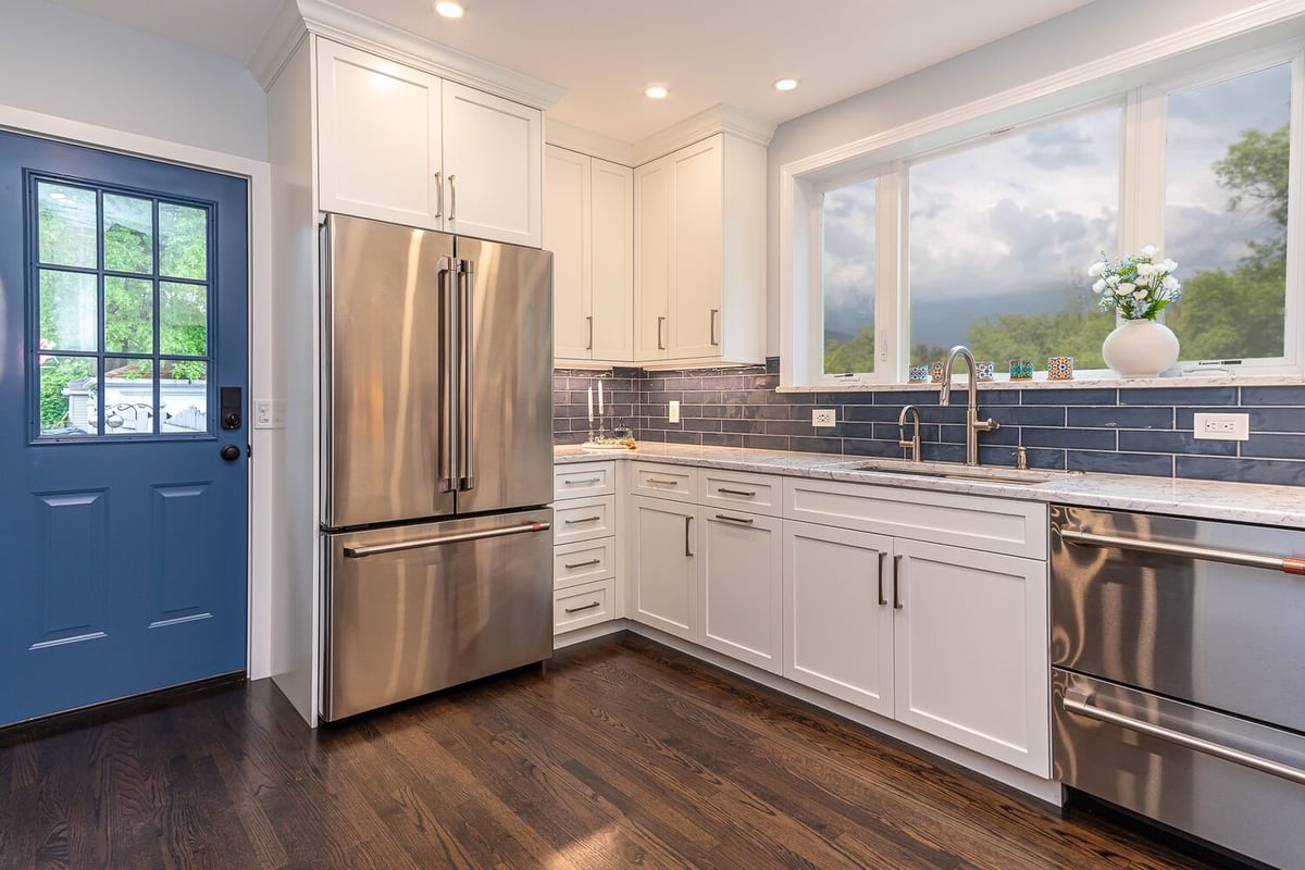 spacious custom home kitchen in Euclid, OH by Chagrin River Company featuring blue backsplash and hardwood flooring.
