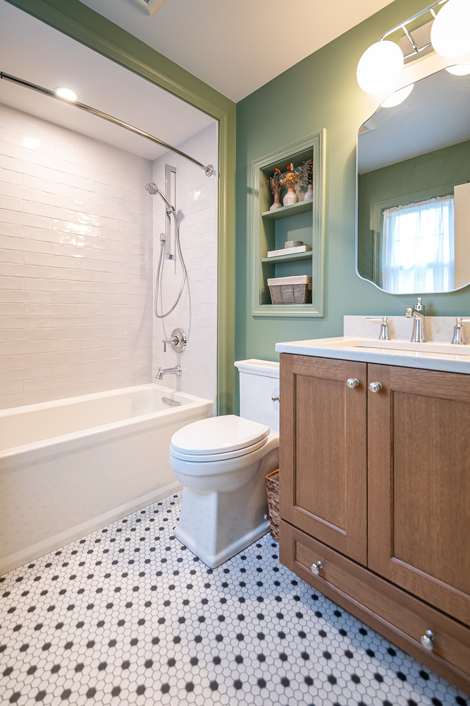 custom home bathroom by Chagrin River Company in Shaker Heights, OH featuring green walls, wood vanity, and white subway tile tub surround.