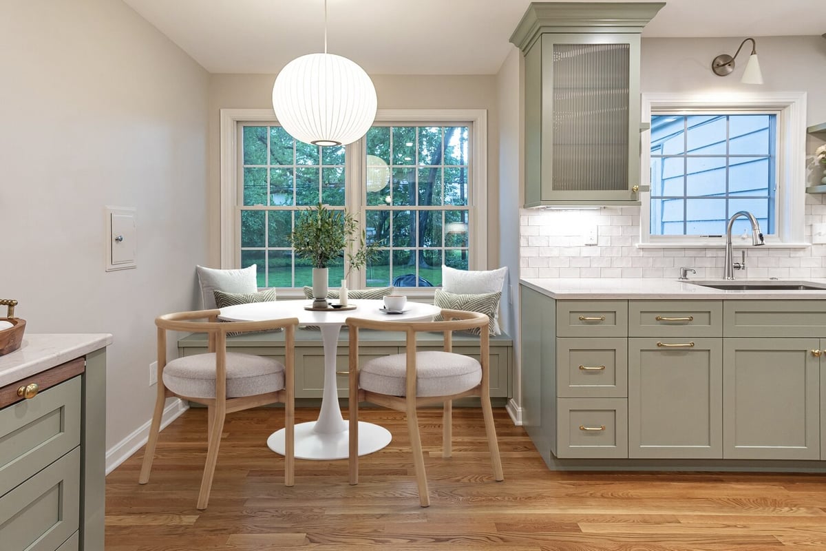 custom home kitchen breakfast nook by Chagrin River Company in Shaker Heights, OH featuring sage green cabinetry, built-in bench seating, and round dining table