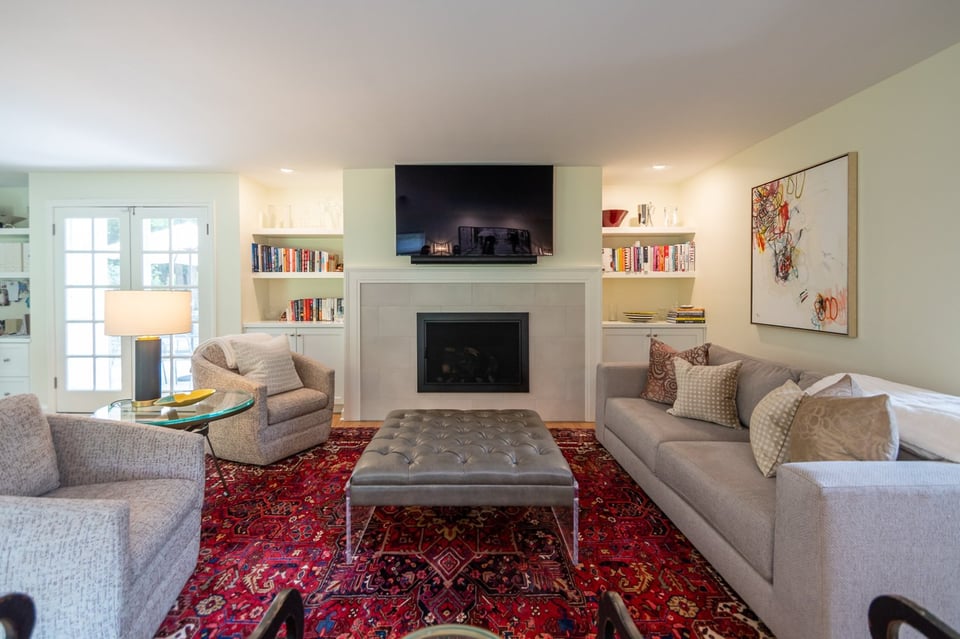 custom home living room by Chagrin River Company in Pepper Pike, OH featuring built-in bookshelves and a modern fireplace with mounted TV.