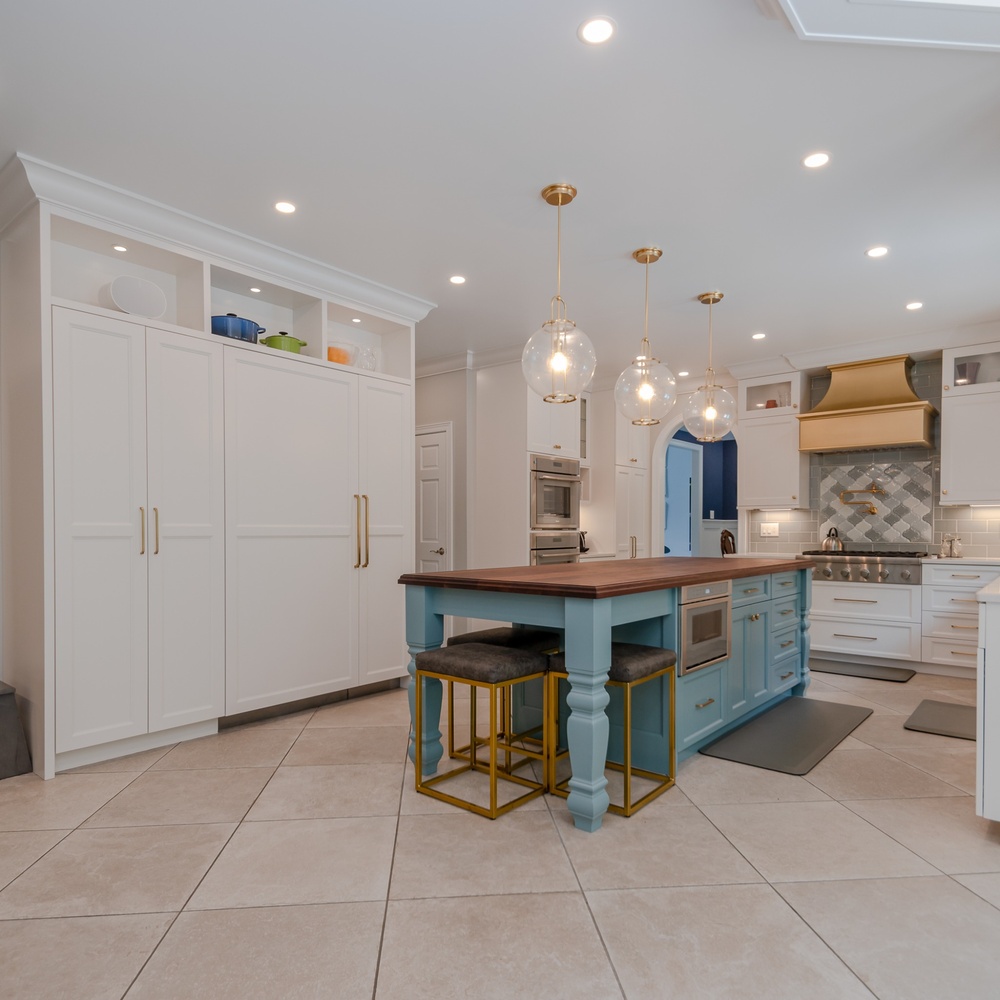 custom home kitchen with blue island and gold stools by Chagrin River Company in Solon, OH