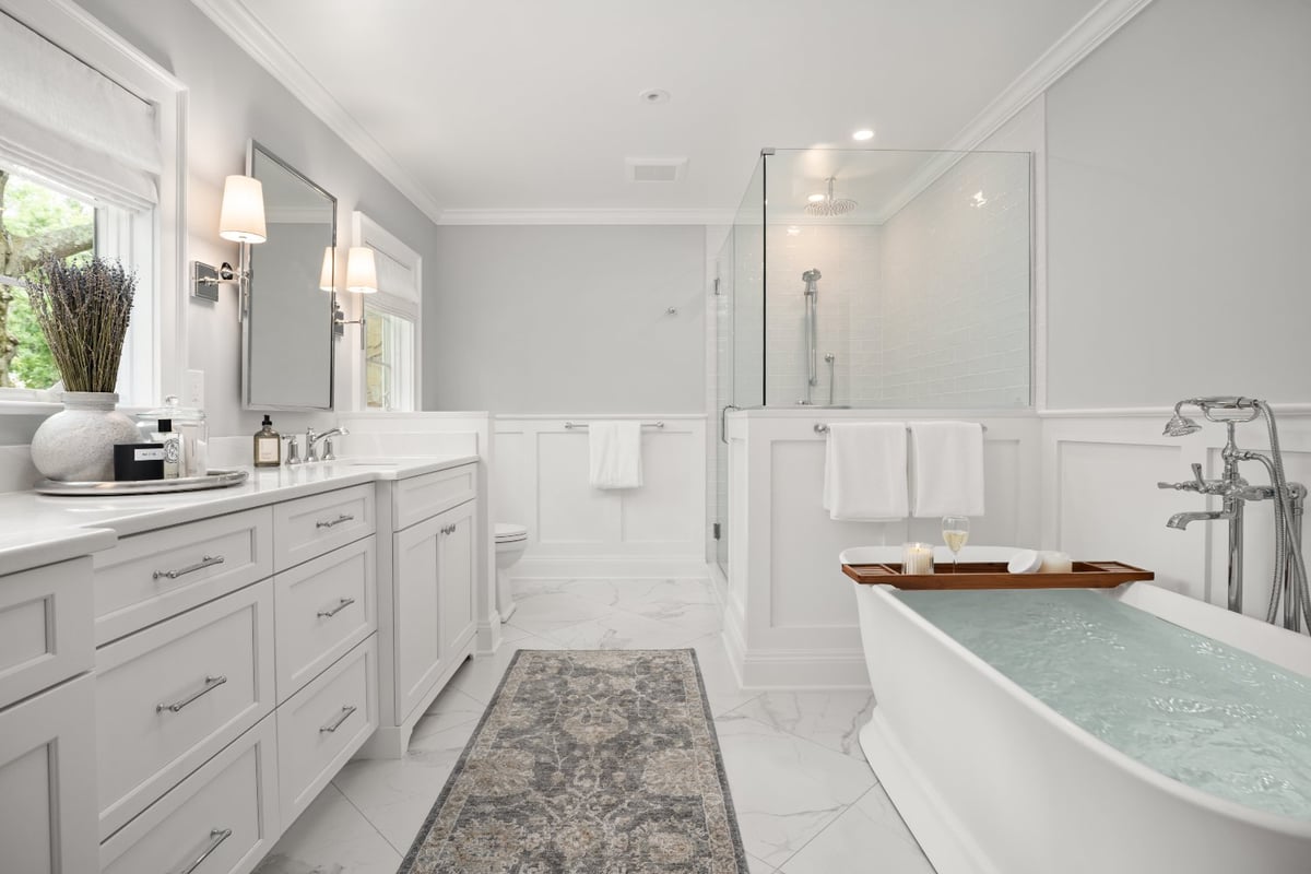 Bright Shaker Heights bathroom by Chagrin River Company with a soaking tub, glass-enclosed shower, white cabinetry, and polished-optimized
