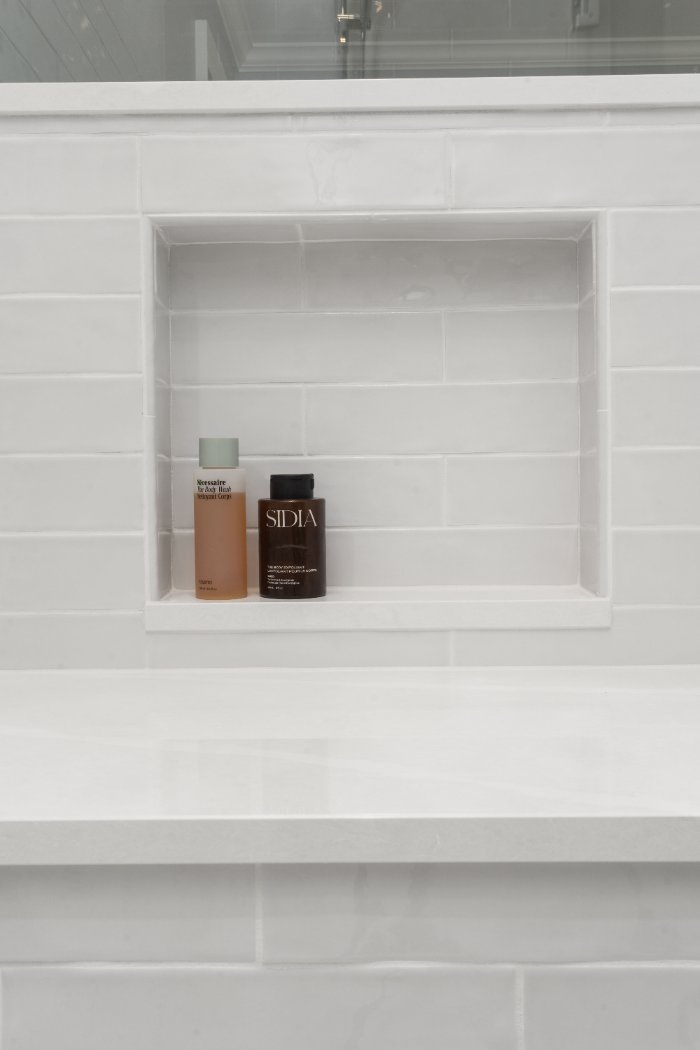 Built-in white tile shower niche with toiletry storage in a Shaker Heights bathroom by Chagrin River Company.-optimized