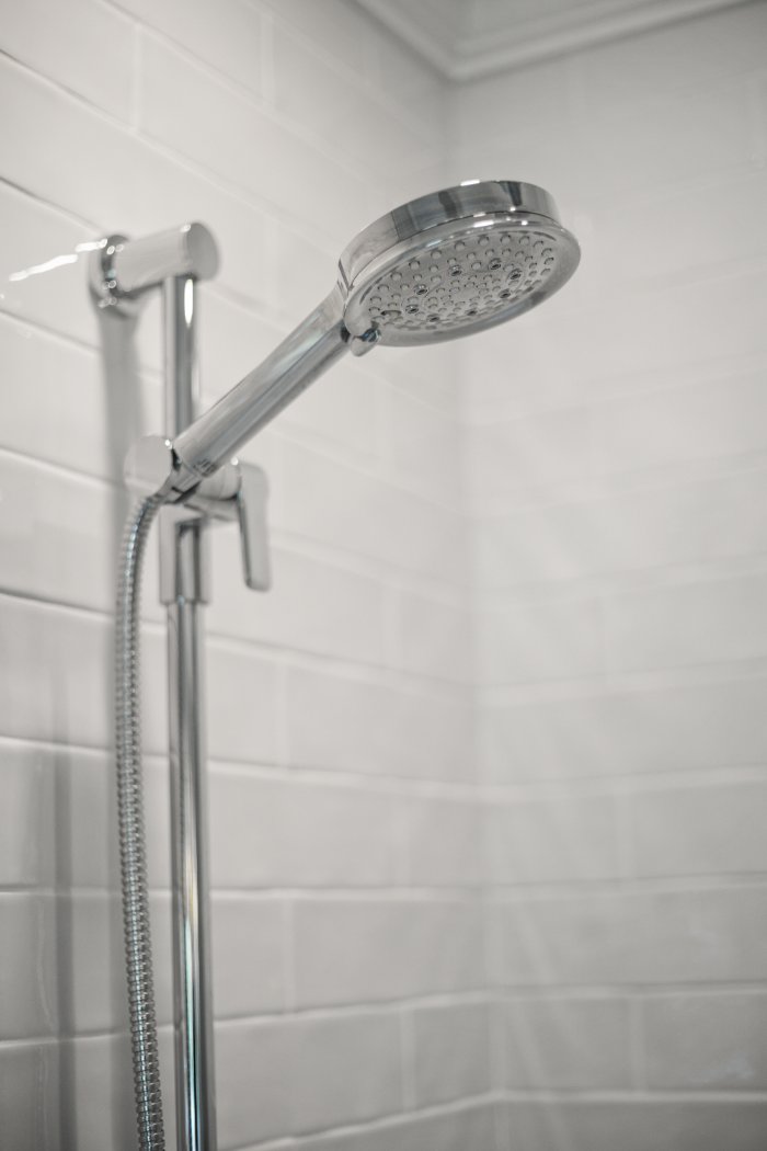 Chrome handheld shower fixture and white subway tile in a Shaker Heights bathroom remodeled by Chagrin River Company.-optimized