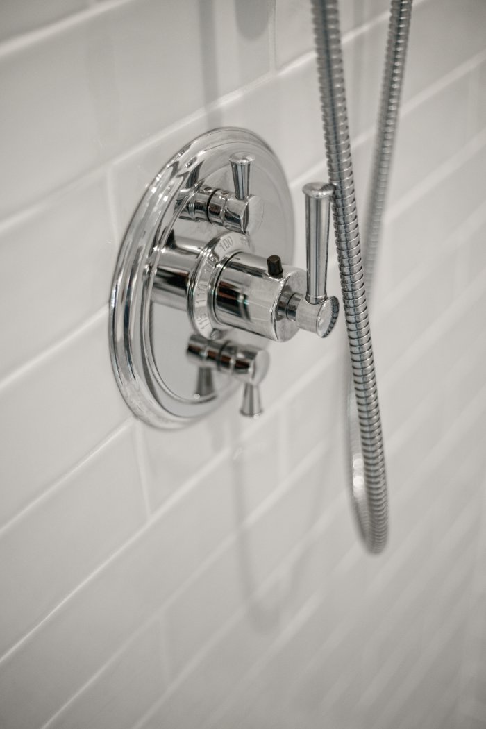 Close-up of chrome shower controls and flexible hose in a Shaker Heights bathroom by Chagrin River Company.-optimized