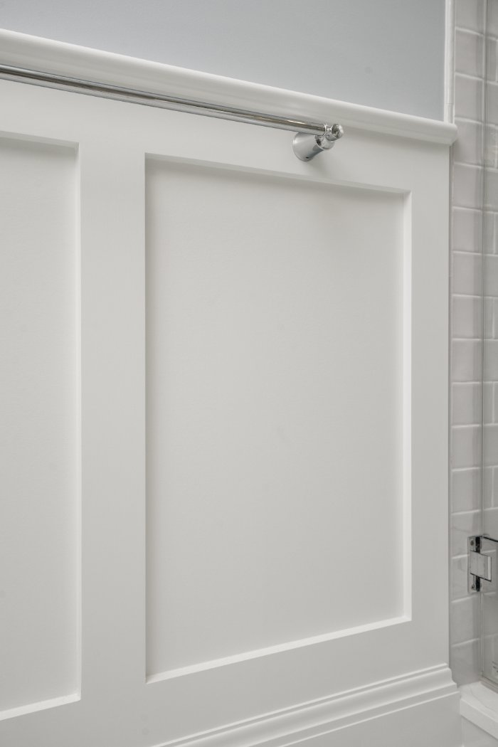 Close-up of white paneled wainscoting and chrome towel hardware in a Shaker Heights bathroom by Chagrin River Company.-optimized