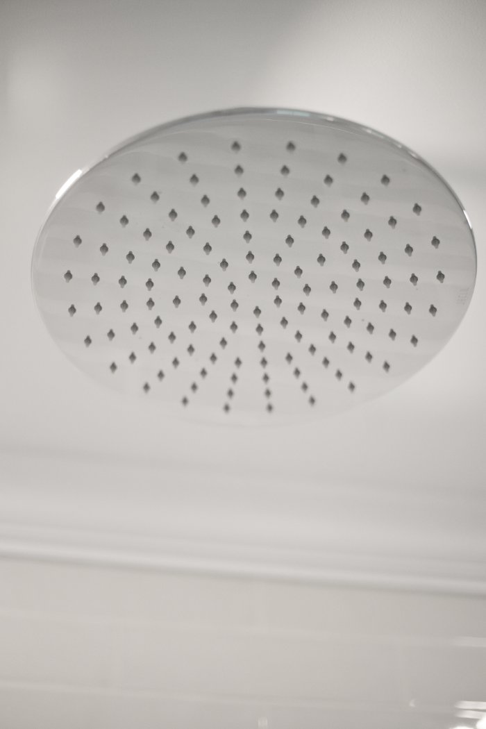 Polished chrome rain showerhead in a Shaker Heights bathroom remodeled by Chagrin River Company.-optimized