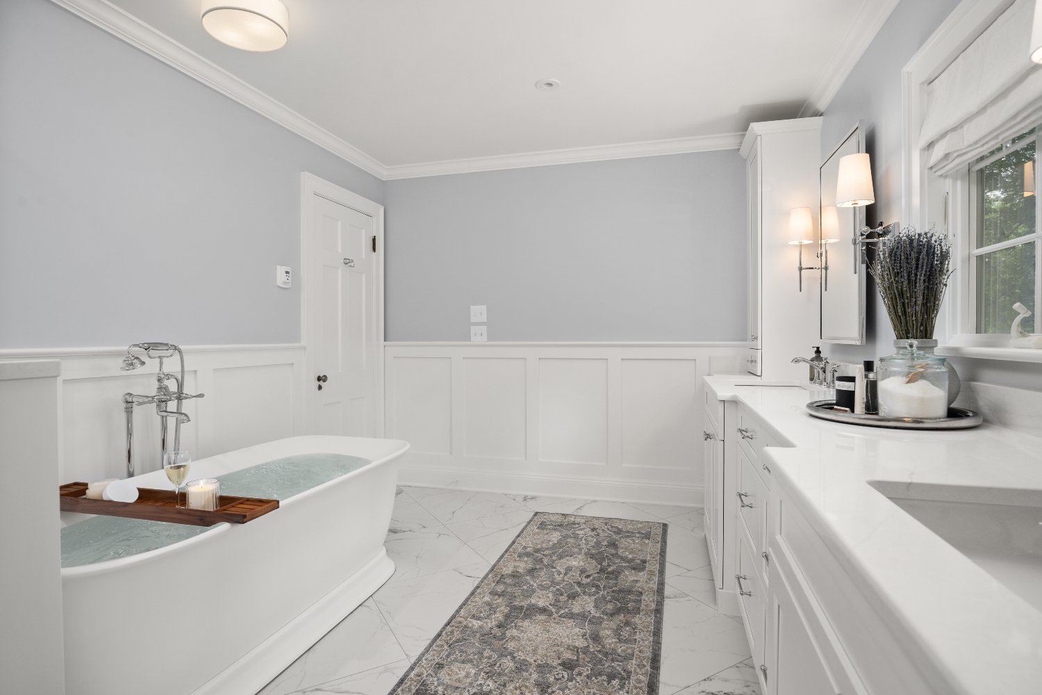Shaker Heights bathroom renovation by Chagrin River Company with freestanding tub, white cabinetry, and paneled walls.-optimized