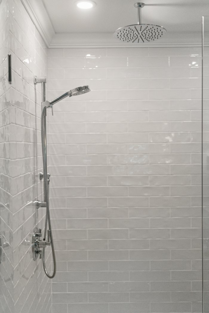 White tiled walk-in shower with chrome rainfall and handheld shower fixtures by Chagrin River Company in Shaker Heights.-optimized