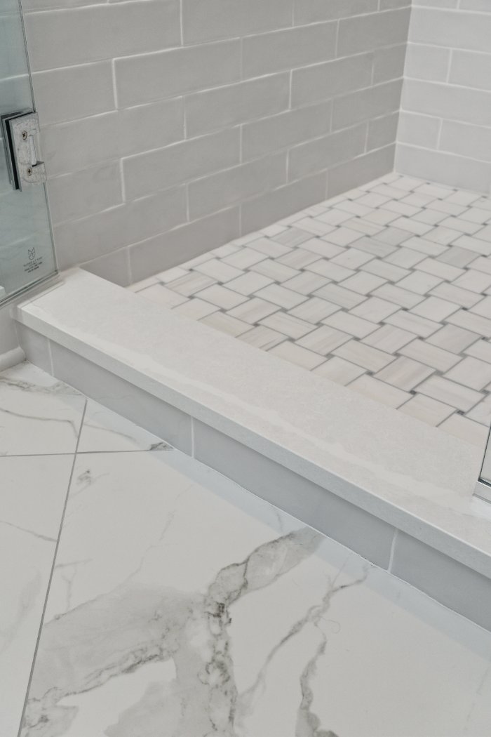 White tiled walk-in shower with glass enclosure and raised threshold by Chagrin River Company in Shaker Heights.-optimized