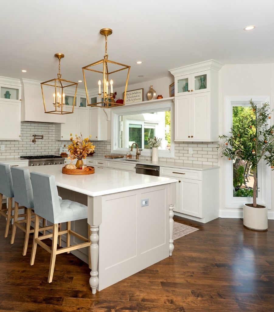 white and gold kitchen renovation with island seating and hardwood floors