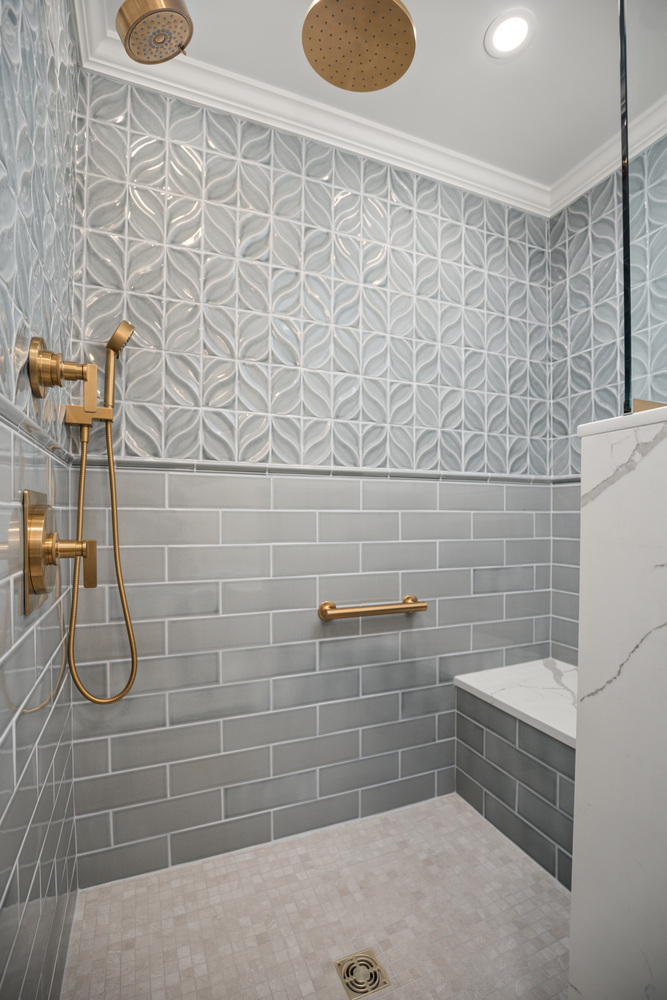 shower wall detail with textured tile and gold handheld fixture by Chagrin River Company in University Heights, OH