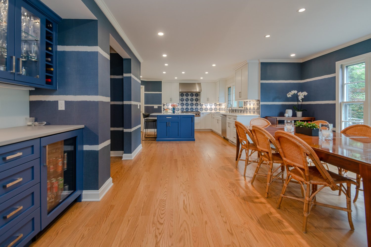 Pepper Pike, OH custom home kitchen by Chagrin River Company featuring blue cabinetry, beverage fridge, and open dining area.